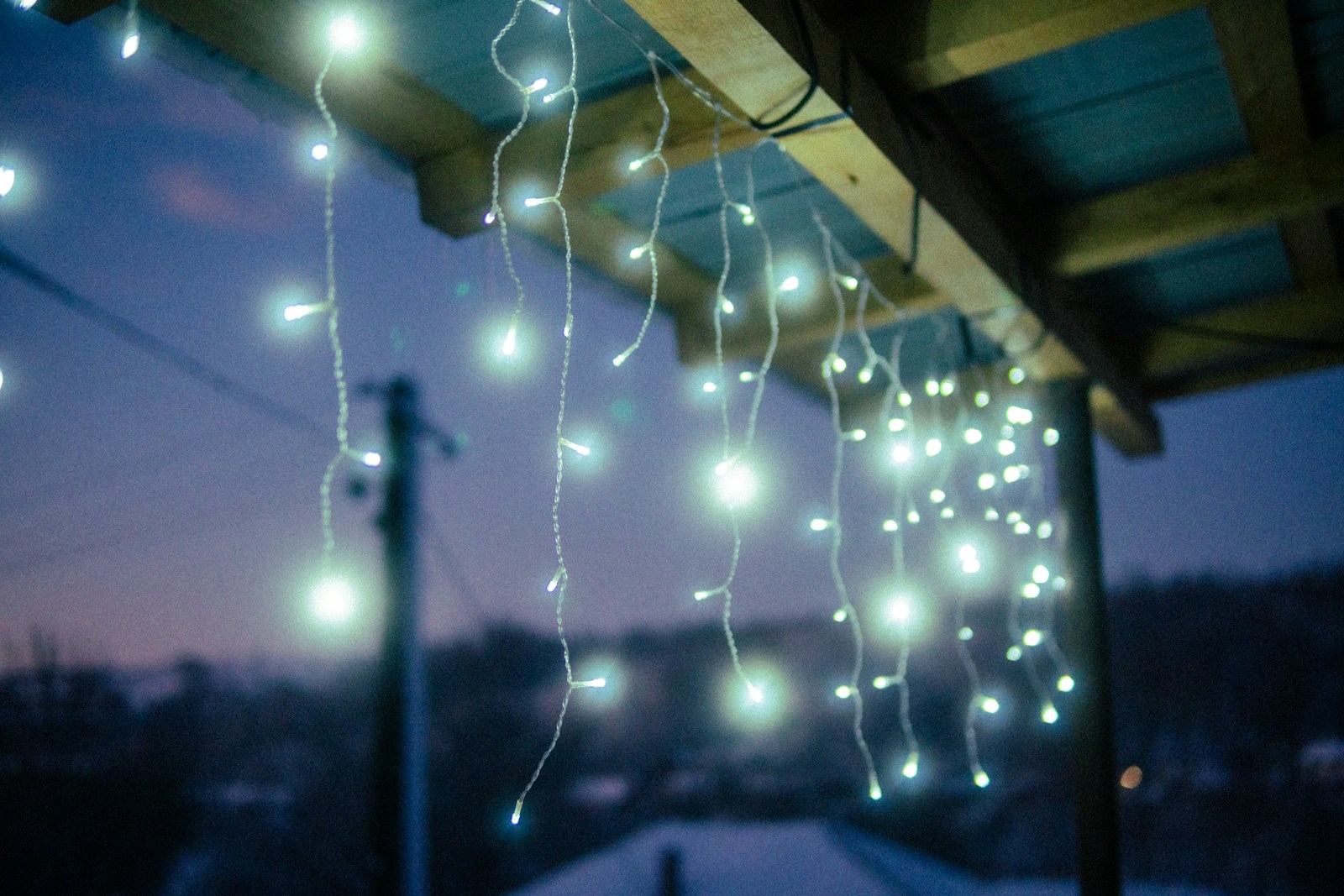 White icicle lights hang from a roof