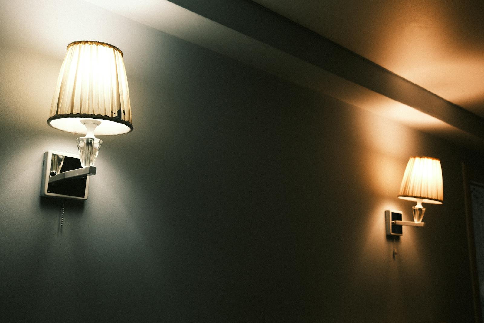 Two elegant wall lamps casting warm, atmospheric light in an indoor setting, creating a cozy ambiance.