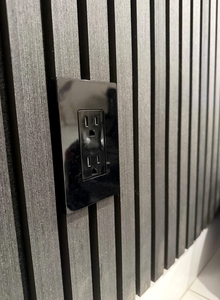 Outlet with a polished metal wall plate on a wood slat accent wall