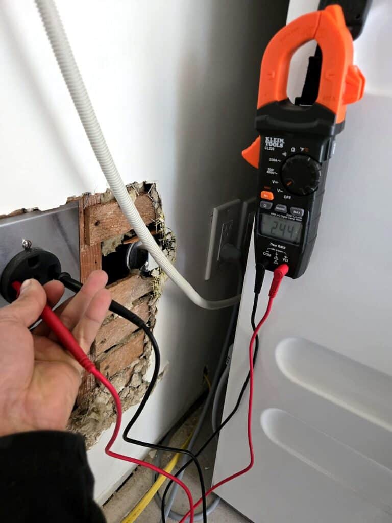 Volta Electric electrician testing an appliance outlet with a clamp meter