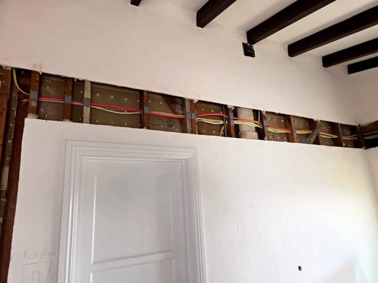 New circuits run through a narrow opening along the top of a wall during a Volta rewire