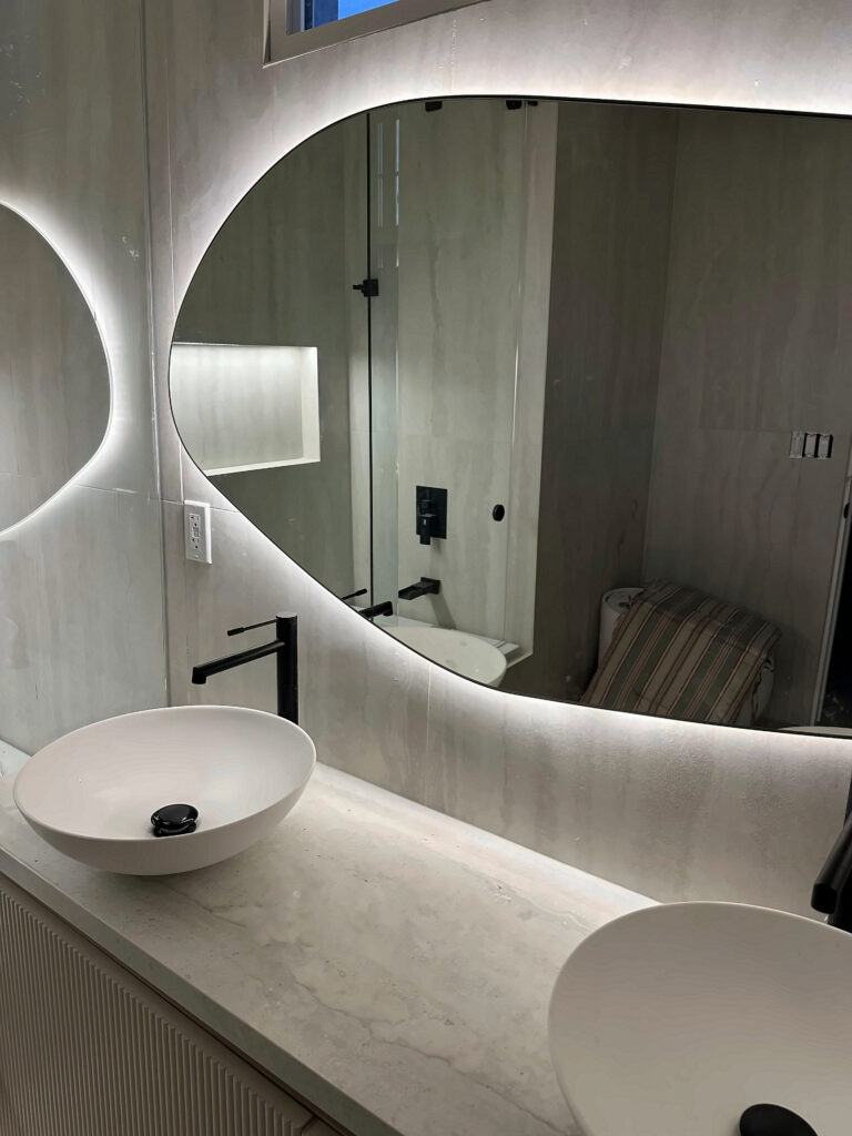 Two LED backlit bathroom mirrors over a stone vanity