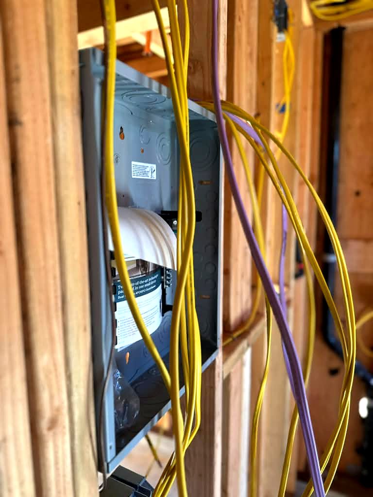 New electrical panel enclosure set in an open stud wall with new circuit cables run to it during rough-in in Tarzana, CA