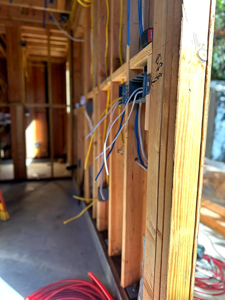 New outlet and switch boxes mounted on wall studs with new wiring during a new-construction rough-in in Tarzana, CA