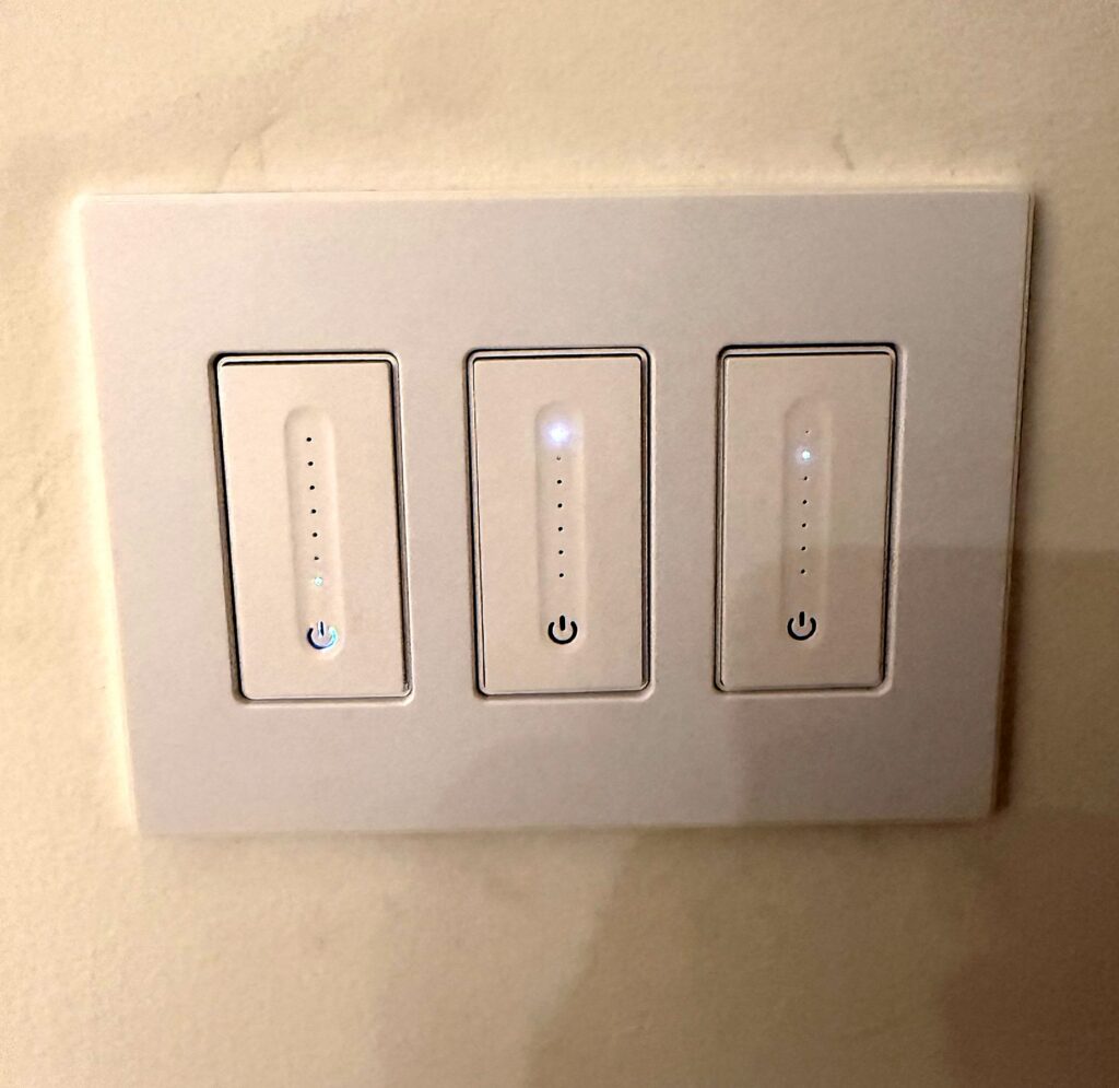Three smart dimmer switches in a screwless white wall plate installed by Volta Electric